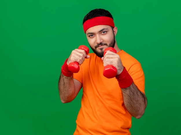 Confiant jeune homme sportif portant bandeau et bracelet debout dans la posture de combat