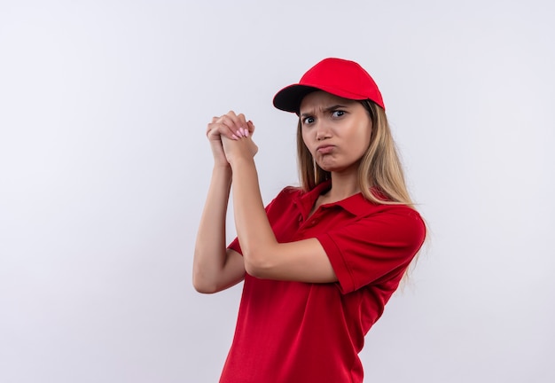 Confiant jeune livreuse portant l'uniforme rouge et une casquette - montrant le geste de poignées de main isolé sur un mur blanc