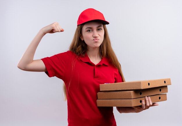 Confiant jeune livreuse en uniforme rouge faisant un geste fort et tenant des paquets sur un espace blanc isolé