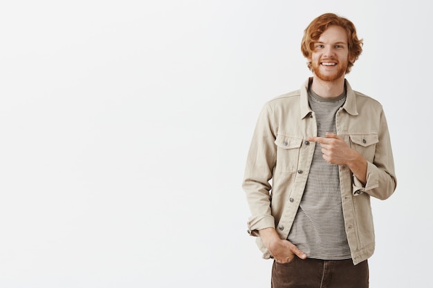 Confiant souriant rousse barbu posant contre le mur blanc