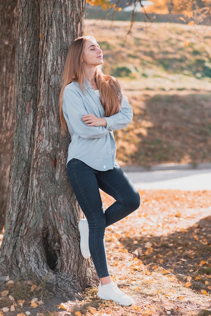 Photo gratuite confiante femme blonde posée sur un arbre