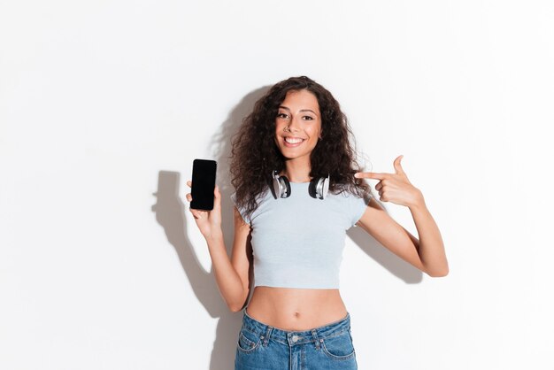 Confiante femme joyeuse pointant sur smartphone