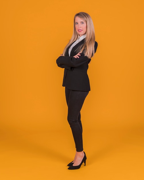 Confiante jeune femme debout sur un fond orange