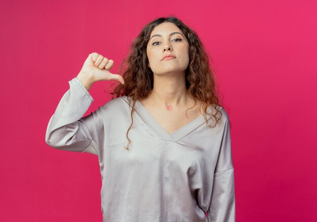 Confiante jeune jolie fille se pointe isolée sur un mur rose