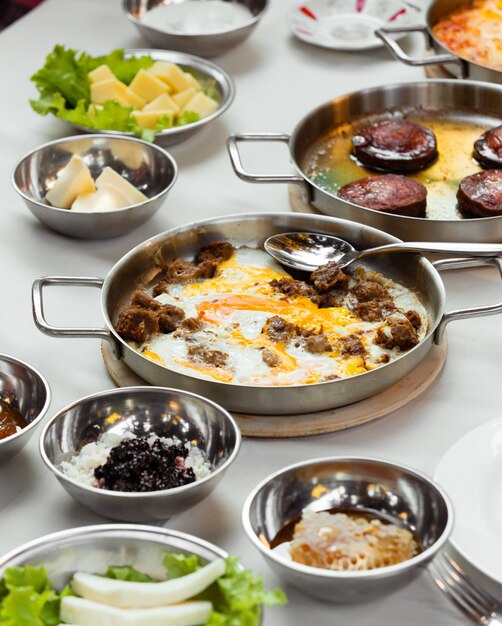 Configuration du petit-déjeuner turc avec oeuf et plat de viande cuit dans une poêle en acier