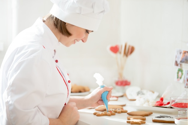 Confiserie souriante professionnelle décorant un gingerman