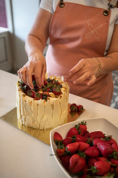 Confiseur féminin avec un gâteau aux fraises dans la pâtisserie