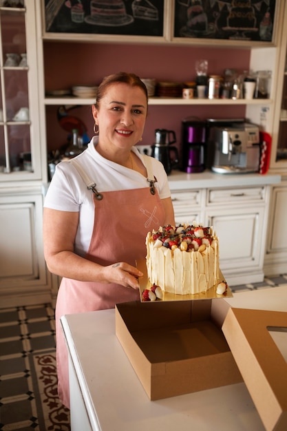 Confiseur féminin avec un gâteau aux fraises dans la pâtisserie