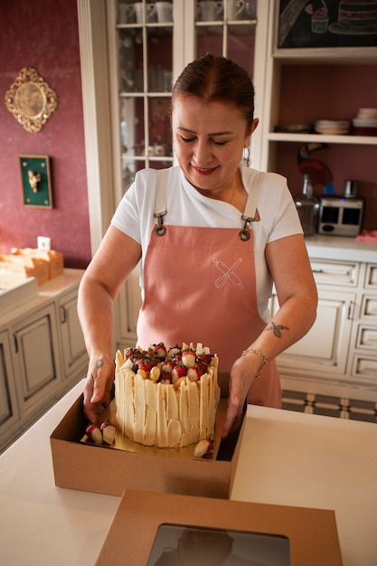 Confiseur féminin avec un gâteau aux fraises dans la pâtisserie