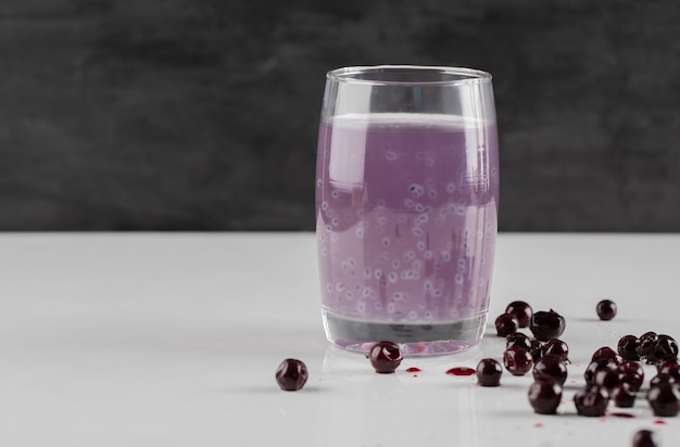 Confiture de cassis avec un verre de jus sur fond blanc.