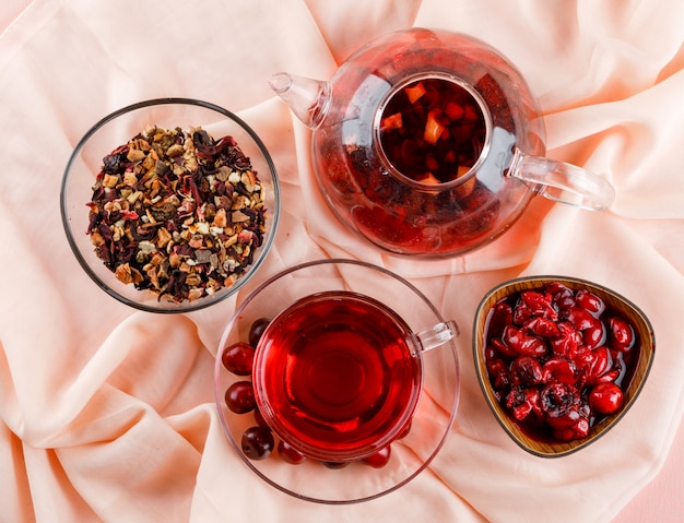 Confiture de cerises dans un bol avec cerises, thé, herbes séchées sur rose et textile