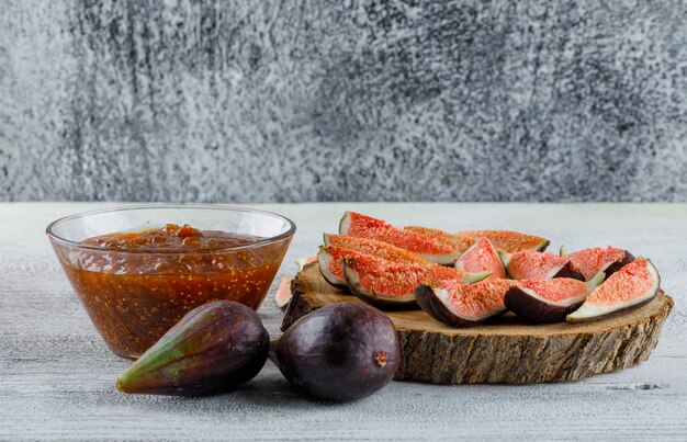 Confiture de figues aux figues dans un bol sur une planche grungy et en bois, vue latérale.