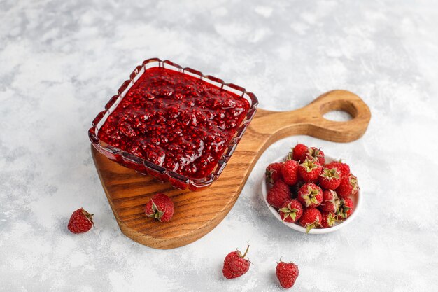 Confiture de framboises faite maison avec des framboises fraîches sur du béton, vue de dessus