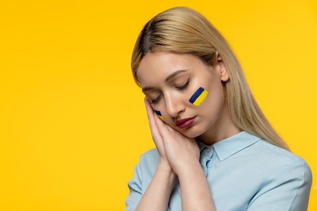 Conflit russe ukrainien jeune jolie fille avec le drapeau ukrainien sur les joues paisibles fermant les yeux
