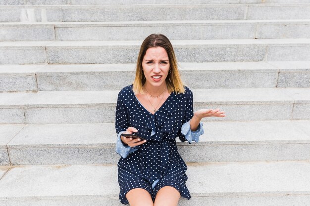 Confondu la jeune femme assise sur l&#39;escalier tenant le smartphone