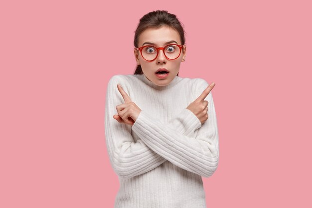 Confus jeune fille de race blanche croise les mains sur la poitrine, indique aux coins gauche et droit