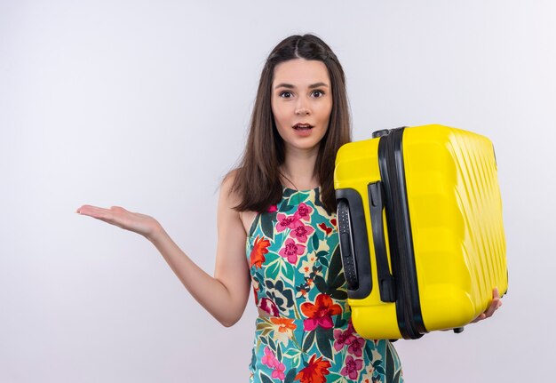 Confus jeune voyageur femme tenant valise sur mur blanc isolé