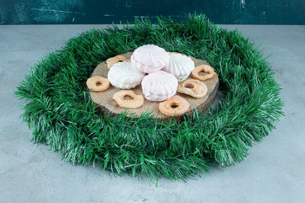 Conseil avec des biscuits et des tranches de pomme sèches dans un cercle de guirlande sur du marbre.