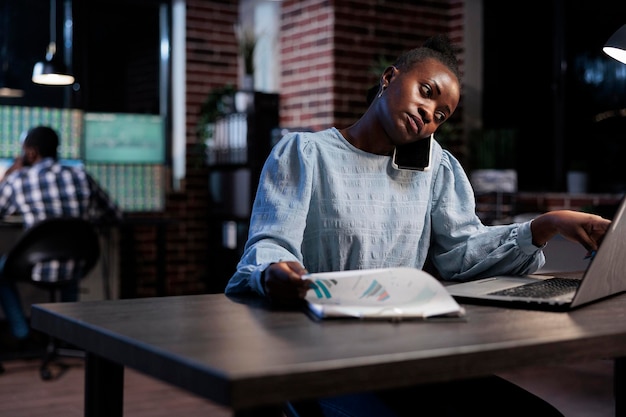 Conseiller en vente dans un espace de travail de bureau, parlant sur un smartphone tout en expliquant le fonds de couverture au client. Conseiller financier assis au bureau tout en parlant au téléphone avec le client de la tendance baissière du marché.