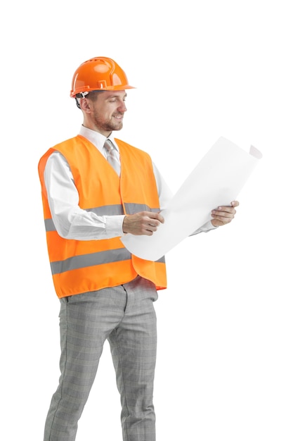 Le constructeur dans un gilet de construction et casque orange debout sur studio blanc