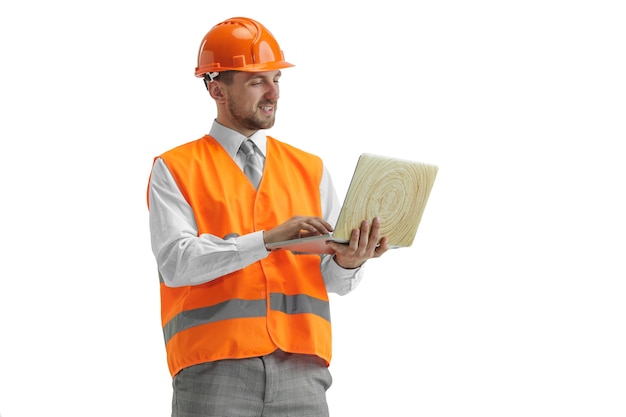 Le Constructeur Dans Un Gilet De Construction Et Un Casque Orange Avec Ordinateur Portable.