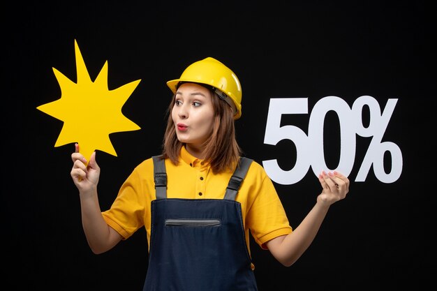 Constructeur féminin de vue de face tenant la figure jaune et sur le mur noir