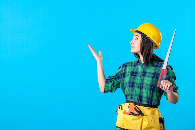 Constructeur Féminin De Vue De Face Tenant La Petite Scie Sur Le Bleu