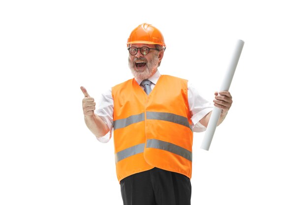 Le constructeur heureux dans un gilet de construction et un casque orange souriant au studio