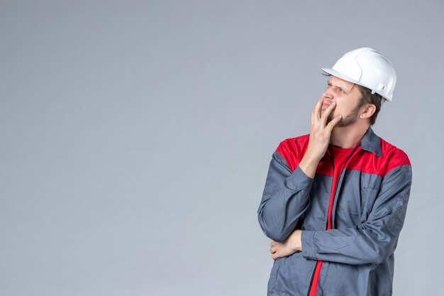 constructeur masculin vue de face en uniforme et casque sur fond gris