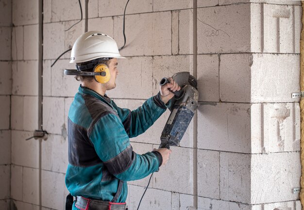 Un constructeur professionnel en vêtements de travail travaille avec un outil de coupe.