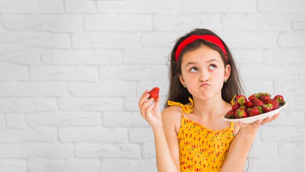 Contemplated girl holding plaque de fraises rouges