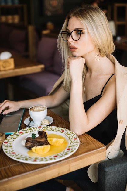 Contemplated jeune femme avec dessert sur la table dans le café