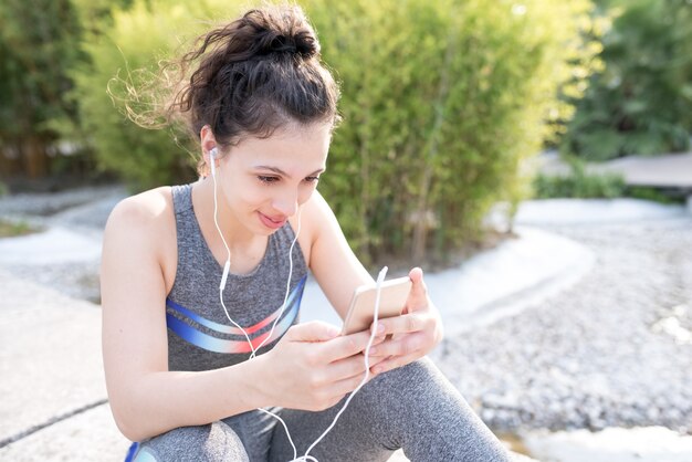 Content Sporty Girl Écouter de la musique dans le parc