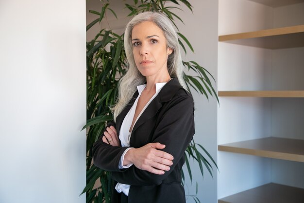 Contenu femme d'affaires caucasienne debout avec les mains jointes. Portrait d'employeur de bureau féminin belle adulte confiant en chemisier noir posant au travail. Concept d'entreprise, d'entreprise et de gestion