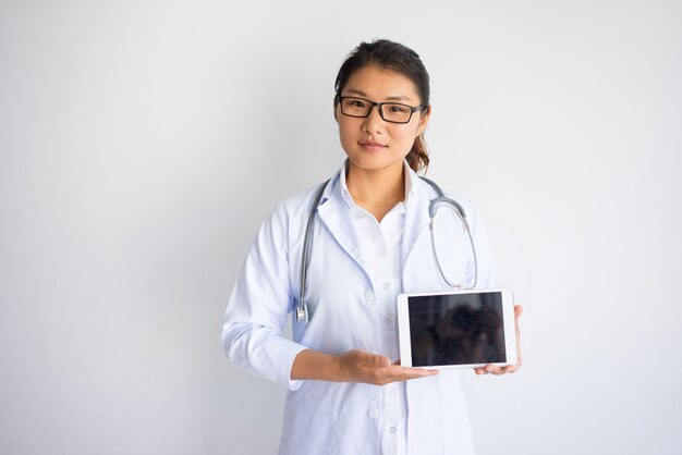 Contenu jeune asiatique femme médecin montrant écran d&#39;ordinateur tablette.