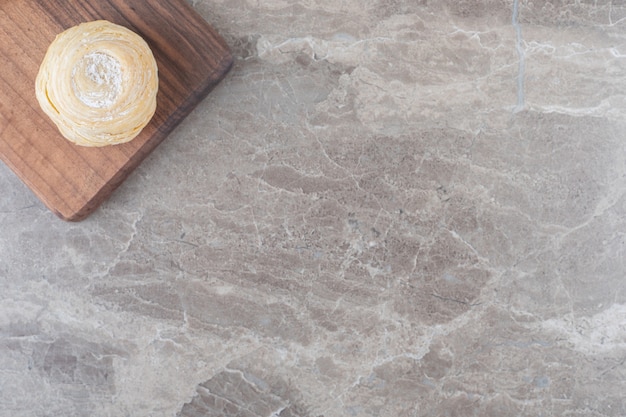 Un cookie feuilleté sur une planche sur une surface en marbre