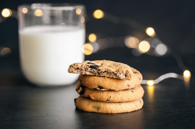 Photo gratuite cookies aux pépites de chocolat classiques et verre de lait sur fond noir