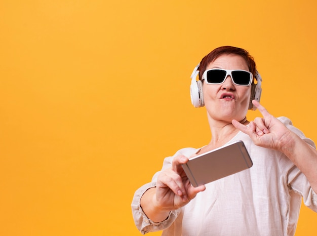 Cool femme senior prenant un selfie