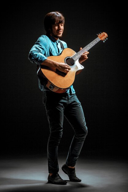 Cool guy debout avec guitare sur fond sombre