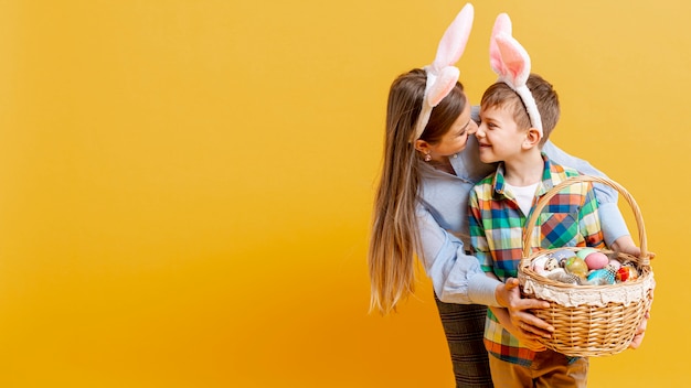 Photo gratuite copie espace mère et fils tenant le panier d'oeufs peints