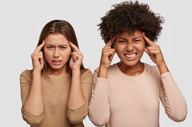 Copines stressantes posant contre le mur blanc