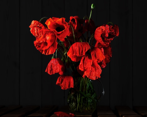Photo gratuite coquelicots en fleurs dans un vase en verre dans l'obscurité