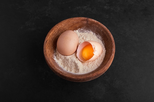 Coquille d'œuf et jaune dans un bol de farine.