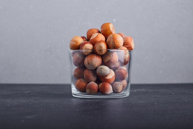 Coquilles de noix dans une tasse en verre sur fond gris.