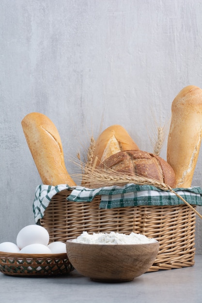 Photo gratuite corbeille à pain, œuf et farine sur une surface en pierre