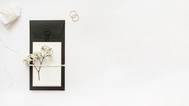 Photo gratuit cordes blanches; bagues de mariage et carte de voeux avec des fleurs d&#39;haleine de bébé sur fond blanc
