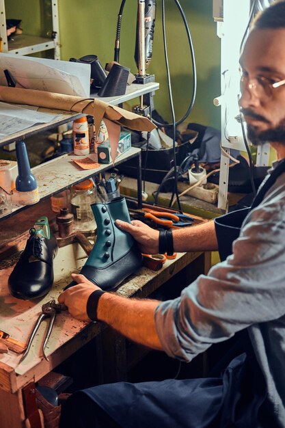 Un cordonnier expérimenté crée des chaussures en cuir rétro dans son confortable atelier.