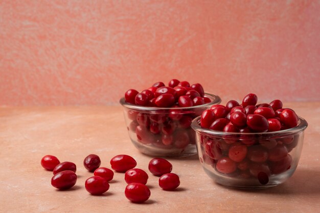 Cornels en coupe en verre sur fond rose.