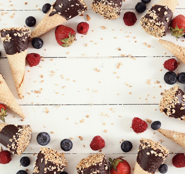 Cornets de crème glacée aux amandes, chocolat et baies sur fond de bois