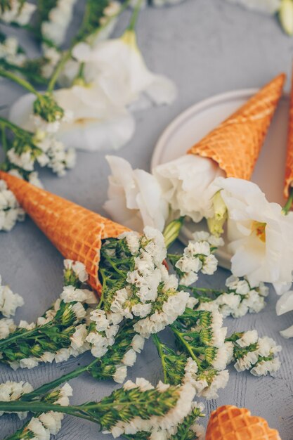 cornets de crème glacée en plaque avec des fleurs sur gris clair. verticale